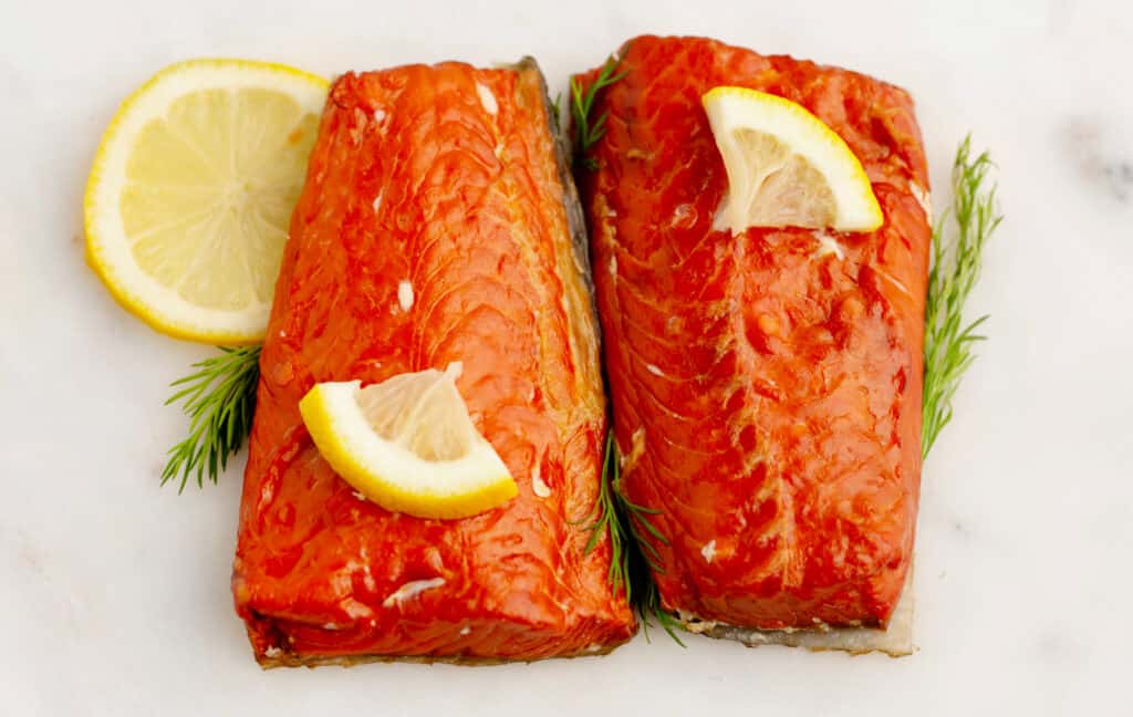 Hot Smoked Salmon Fillets with Lemon and Herbs on White Marble