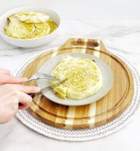 Cutting and Eating Cabbage Steaks with Fork and Knife on Plate