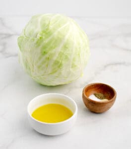 Head of Cabbage, Olive Oil, and Seasonings on White Marble Surface