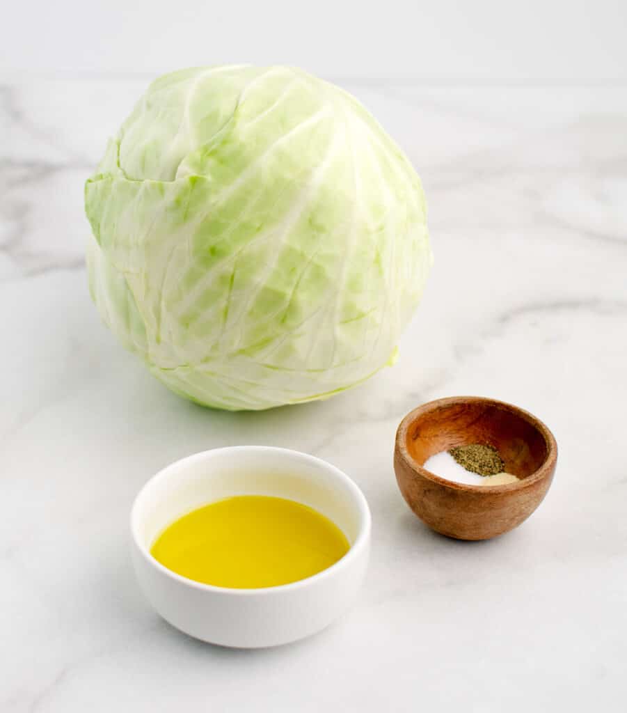 Head of Cabbage, Olive Oil, and Spices on White Marble Surface