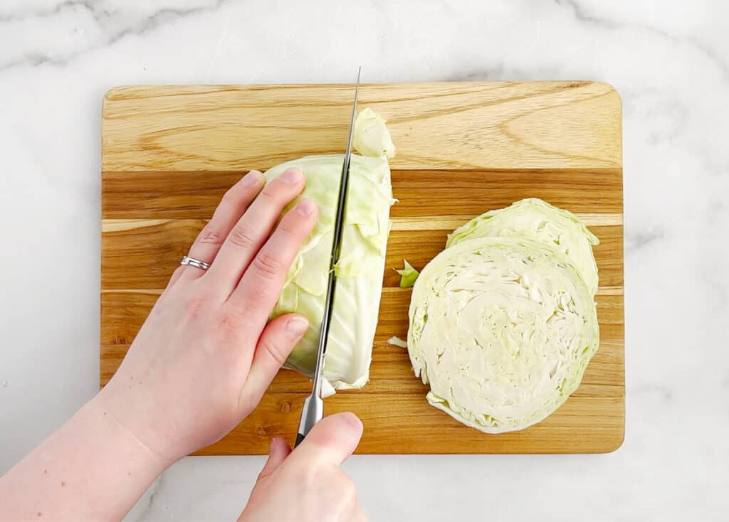 Cutting Head of Cabbage with Knife on Cutting Board