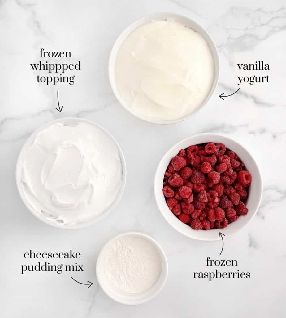 Whipped Topping, Vanilla Yogurt, Frozen Raspberries, Pudding Mix in White Bowls on Marble Counter