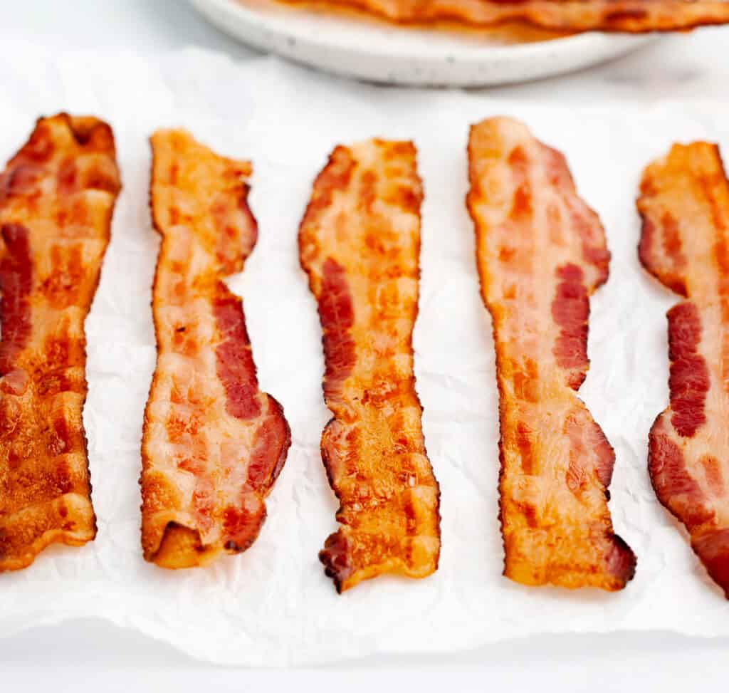 Bacon on Parchment with Plate of Bacon in Background