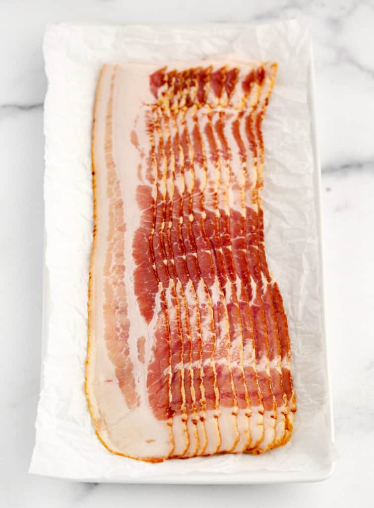 Raw Bacon Slices on White Plate