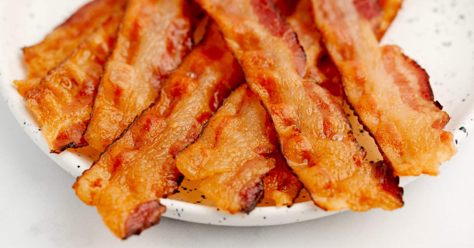 Bacon frying in stove top pan. Sizzling bacon strips in silver skillet.  Stock Photo