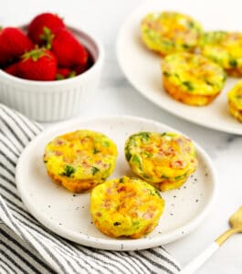 Egg Bites on Plate with Egg Bites and Strawberries in the Background
