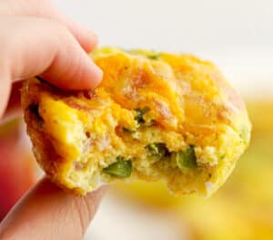 Hand Holding Egg Bite with Bacon and Veggies