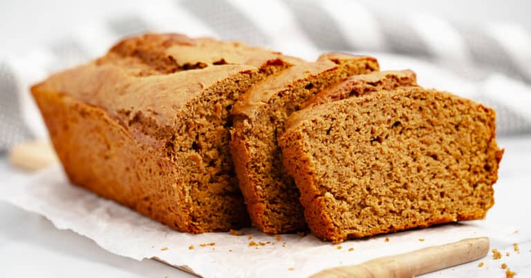 Pumpkin Bread Sliced on Wooden Board and Parchment with Striped Towel in the Background