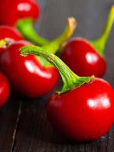 Close up of Cherry Peppers with stems on a dark background
