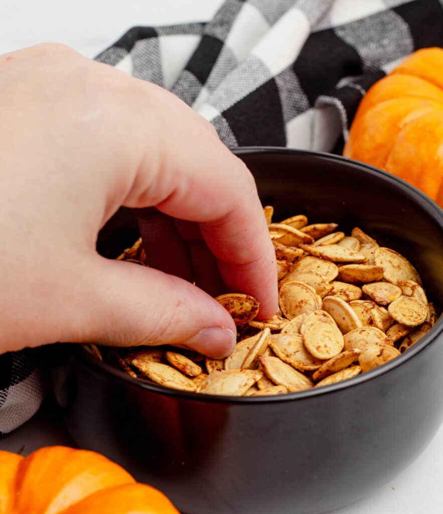 Hand Grabbing Pumpkin Seeds from Bowl