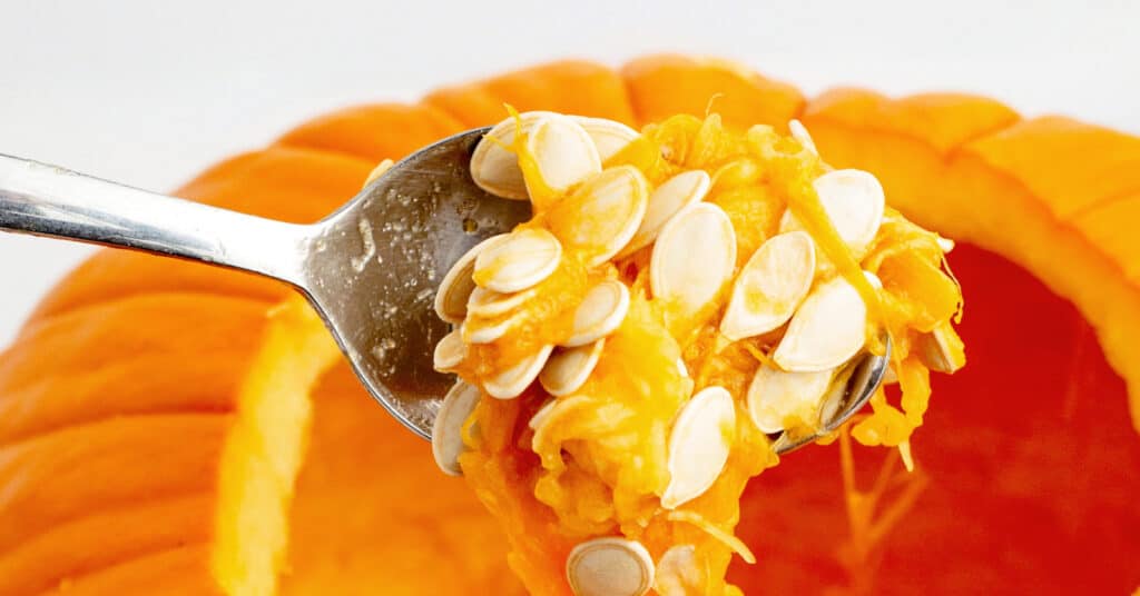 Scooping Pumpkin Seeds Out of Pumpkin with Spoon