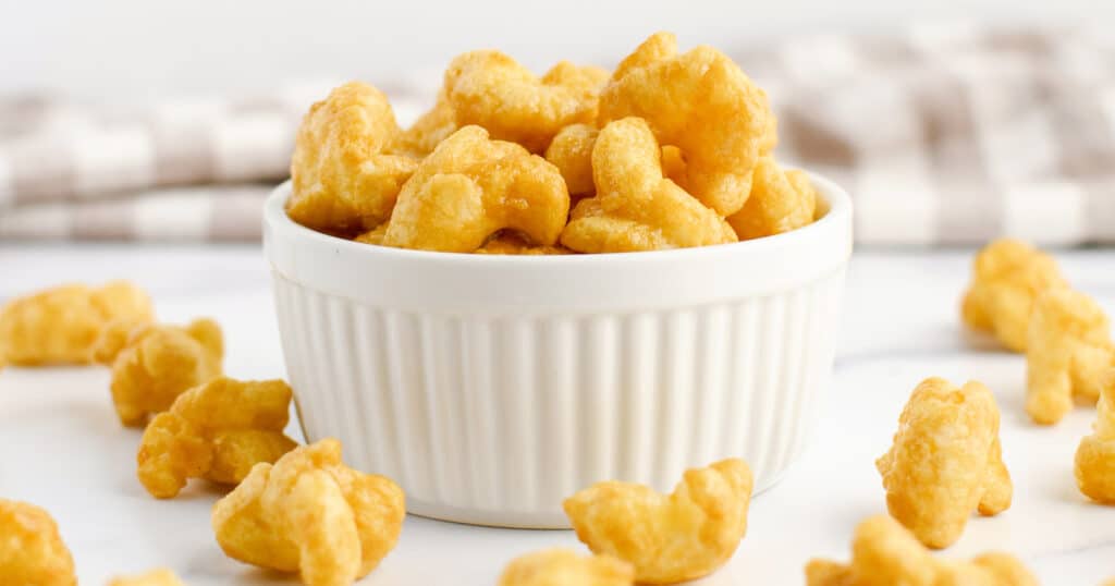 Caramel Puff Corn in White Bowl with Puff Corn and Kitchen Towel Surrounding