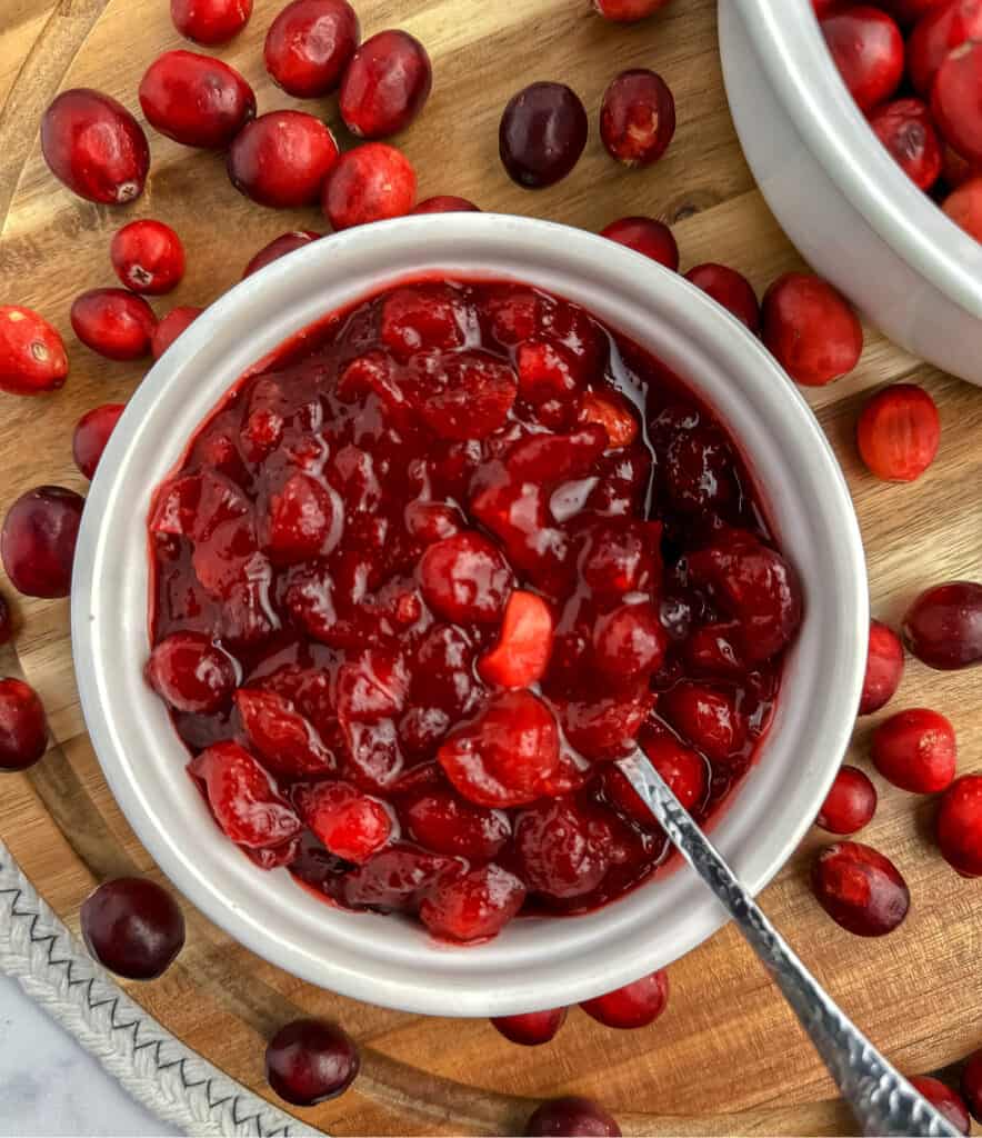 Cranberry Sauce in Bowl with Spoon Surrounding by Fresh Cranberries