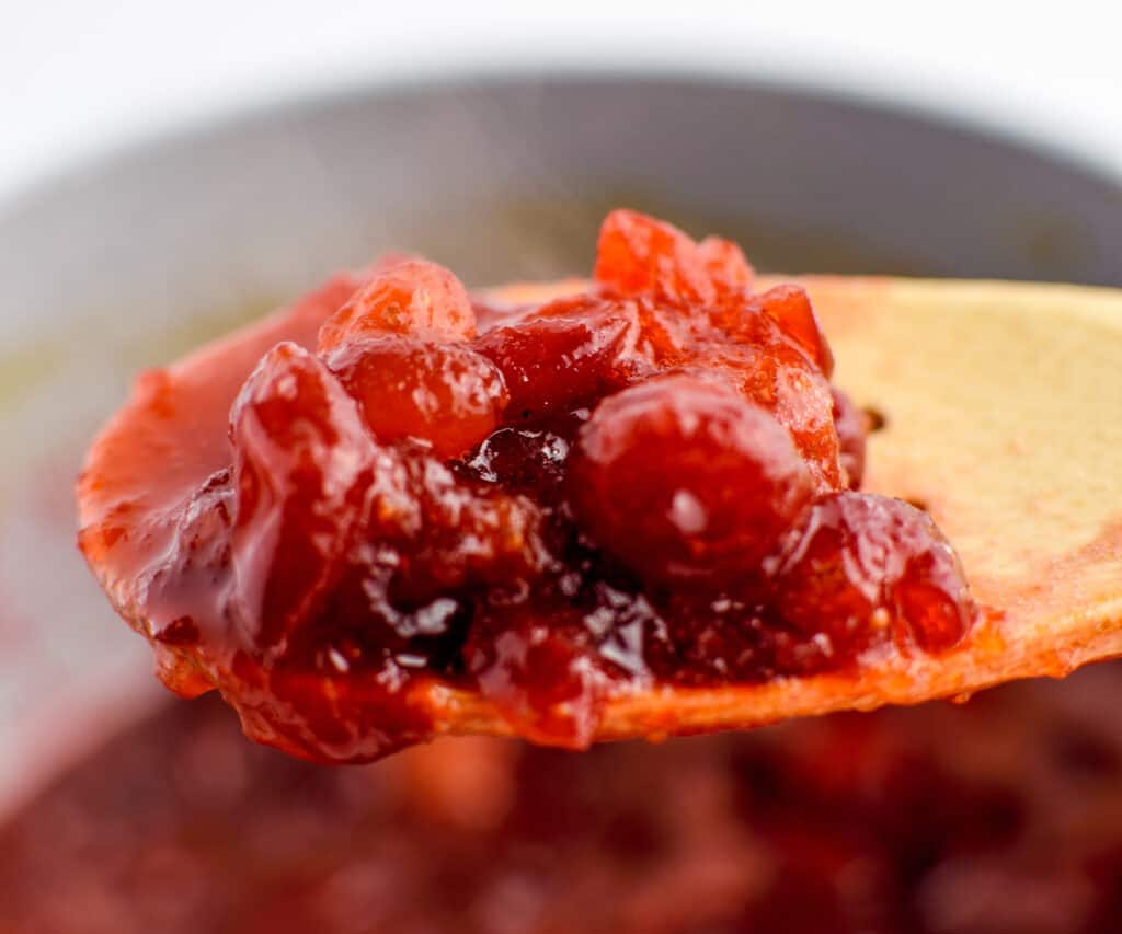 Cranberry Sauce on Wooden Spoon with Saucepan in Background