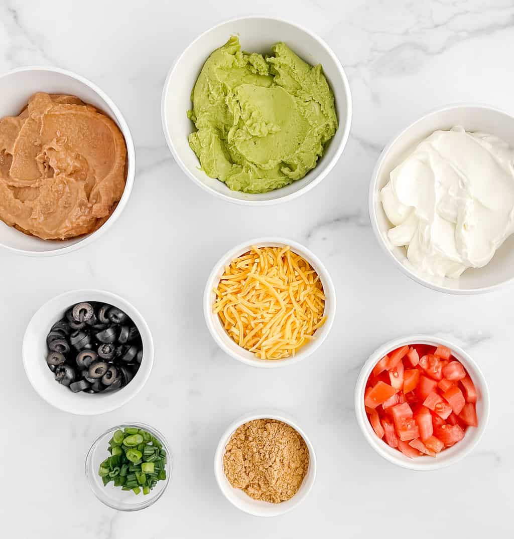 Bowls of Ingredients for Taco Dip on White Marble Surface