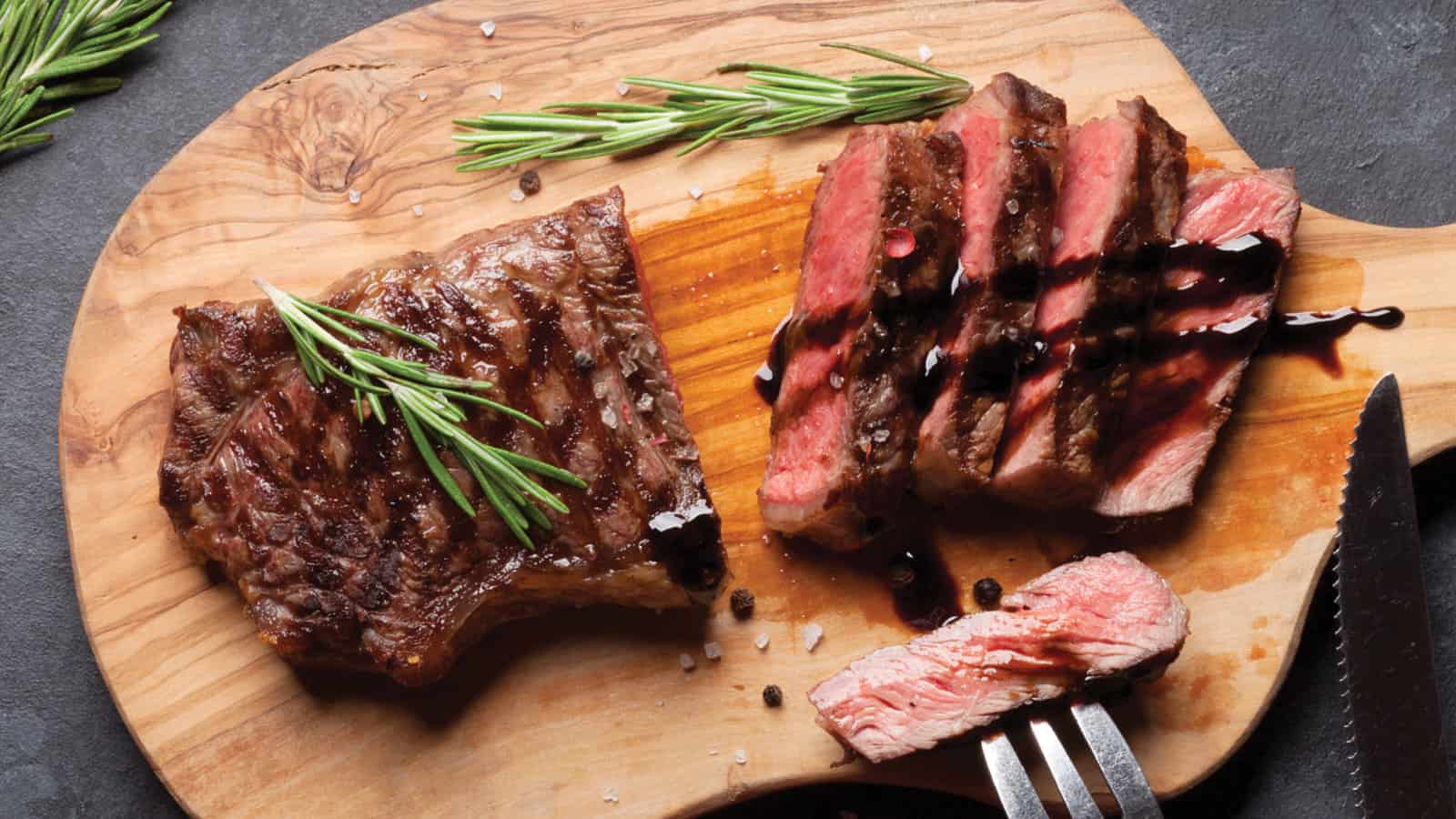 Steak with Sauce Topping and Herbs on Wooden Cutting Board