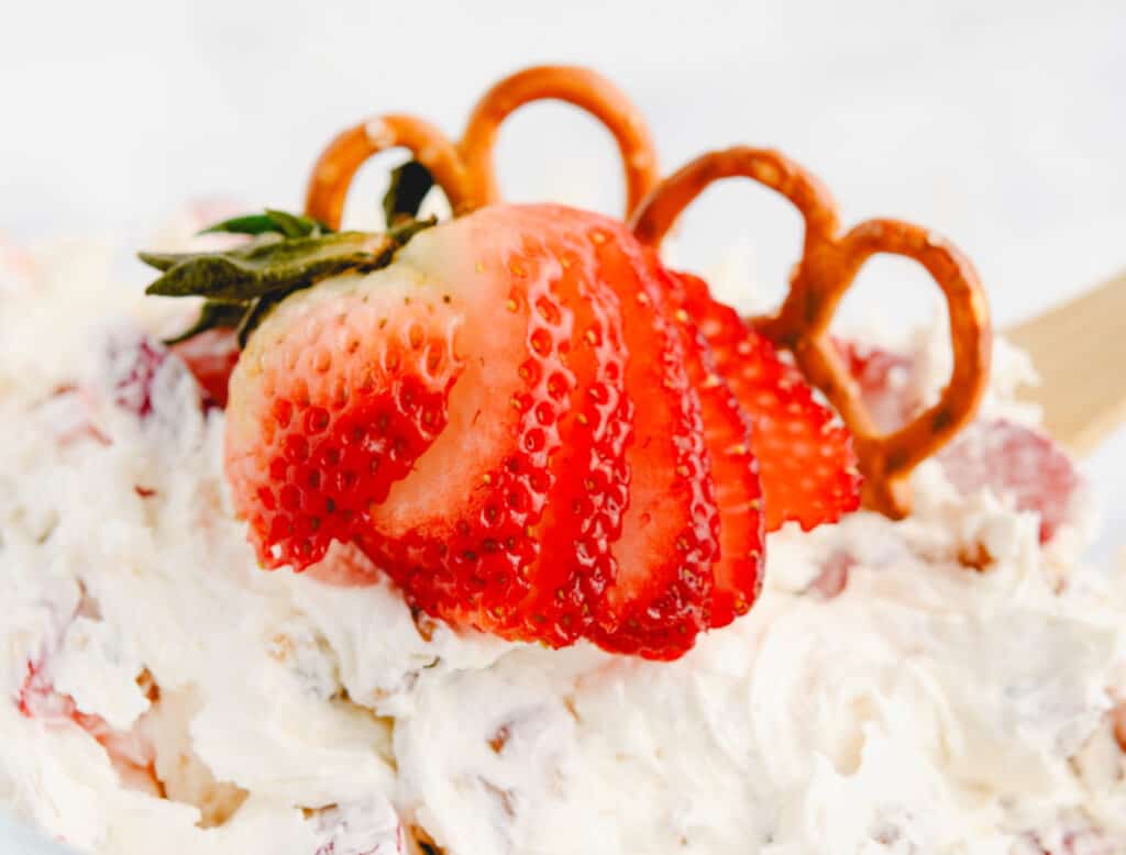 Strawberry Pretzel Salad in a Bowl Garnished with a Fresh Strawberry and Pretzels