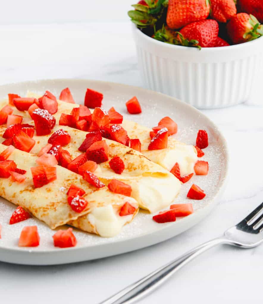 Strawberry Cream Cheese Crepes on Plate with Fork and Strawberries in a Bowl