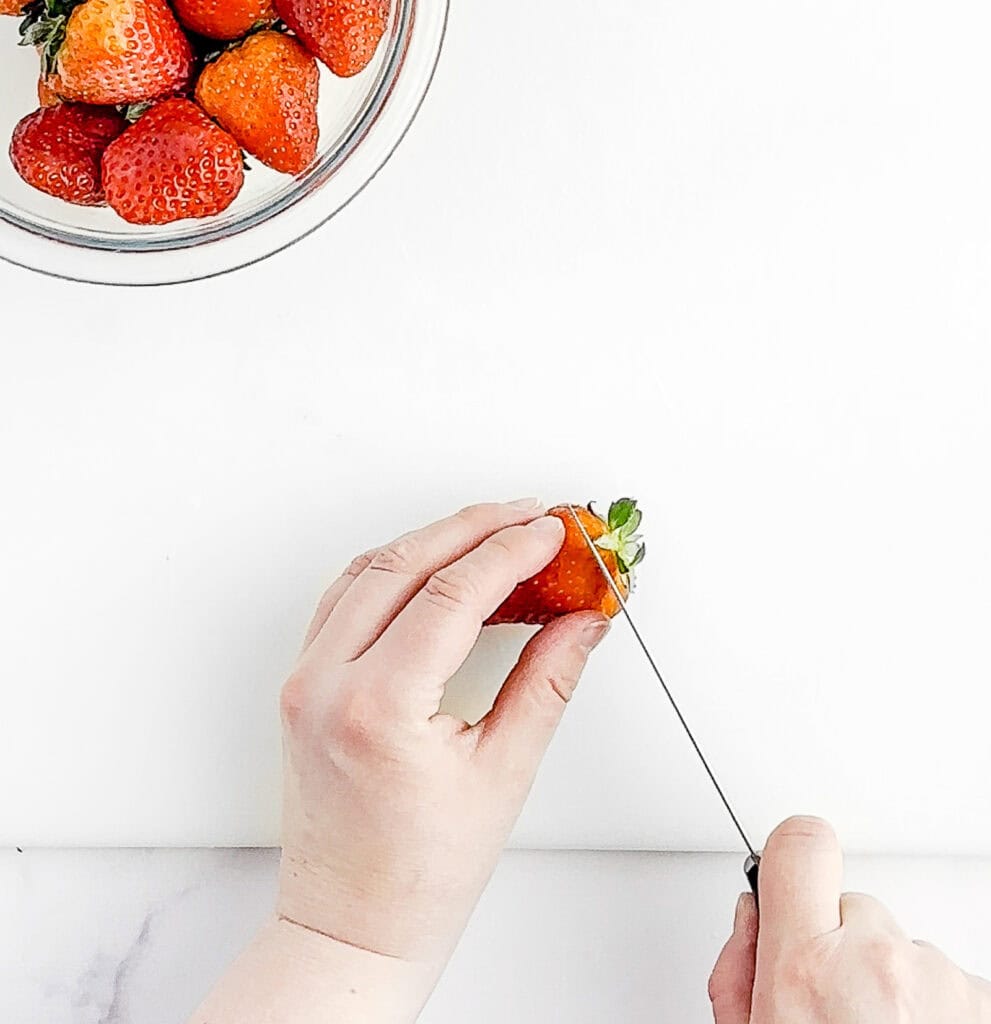 Cutting the Top Off of a Strawberry with Bowl of Strawberries