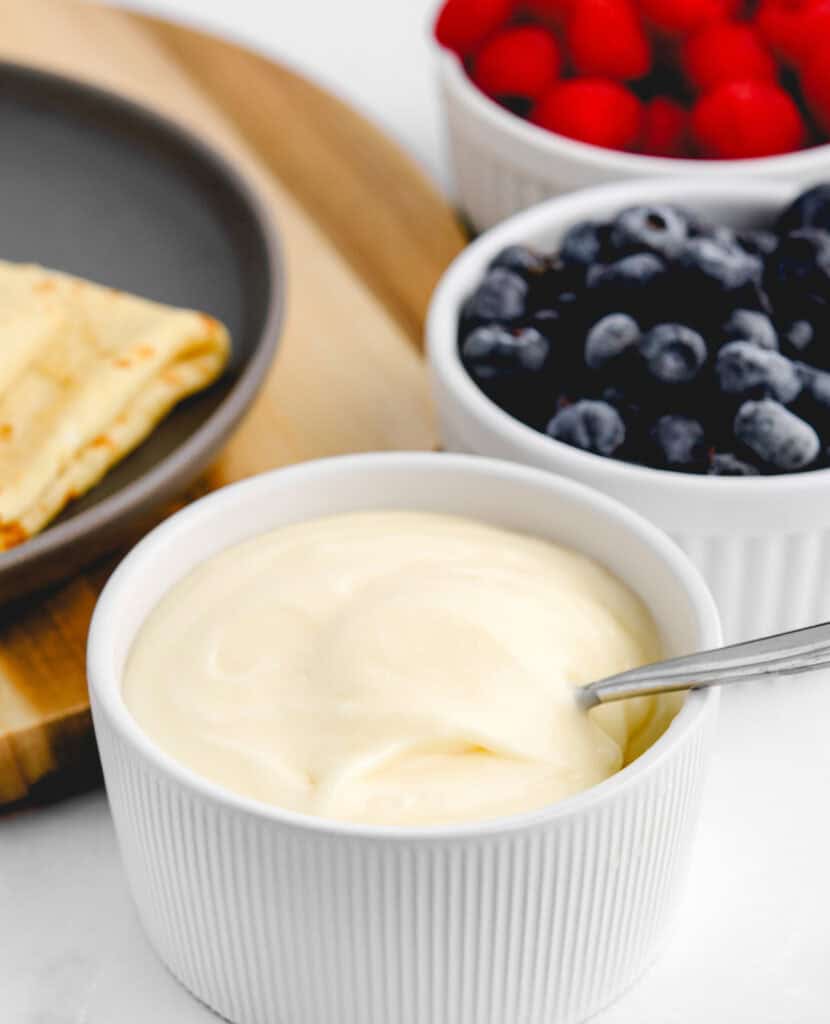 Cream Cheese Filling in Bowl with Spoon and Blueberries and Raspberries Behind