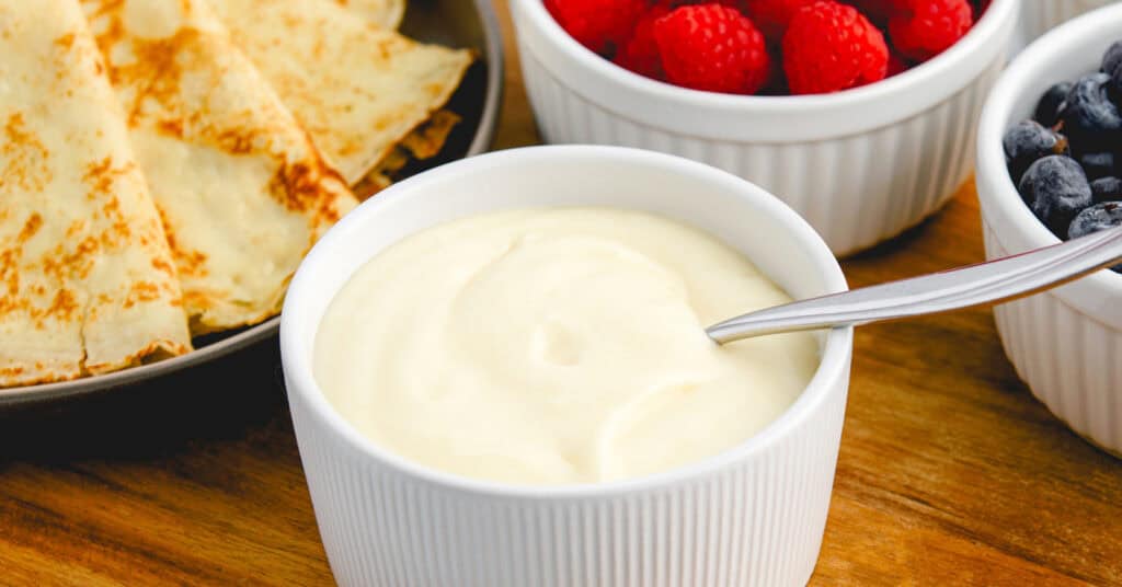 Sweet Cream Cheese Crepe Filling in Bowl with Berries and Crepes in the Background