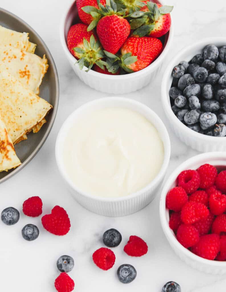 Top View of Sweet Cream Cheese Filling in Bowl with Berries and Crepes Around