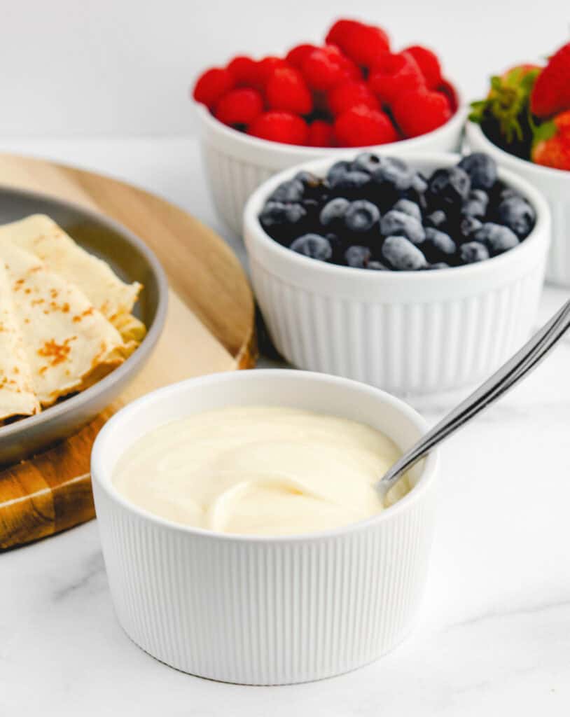Sweetened Cream Cheese Mixture in Bowl with Berries and Crepes Behind