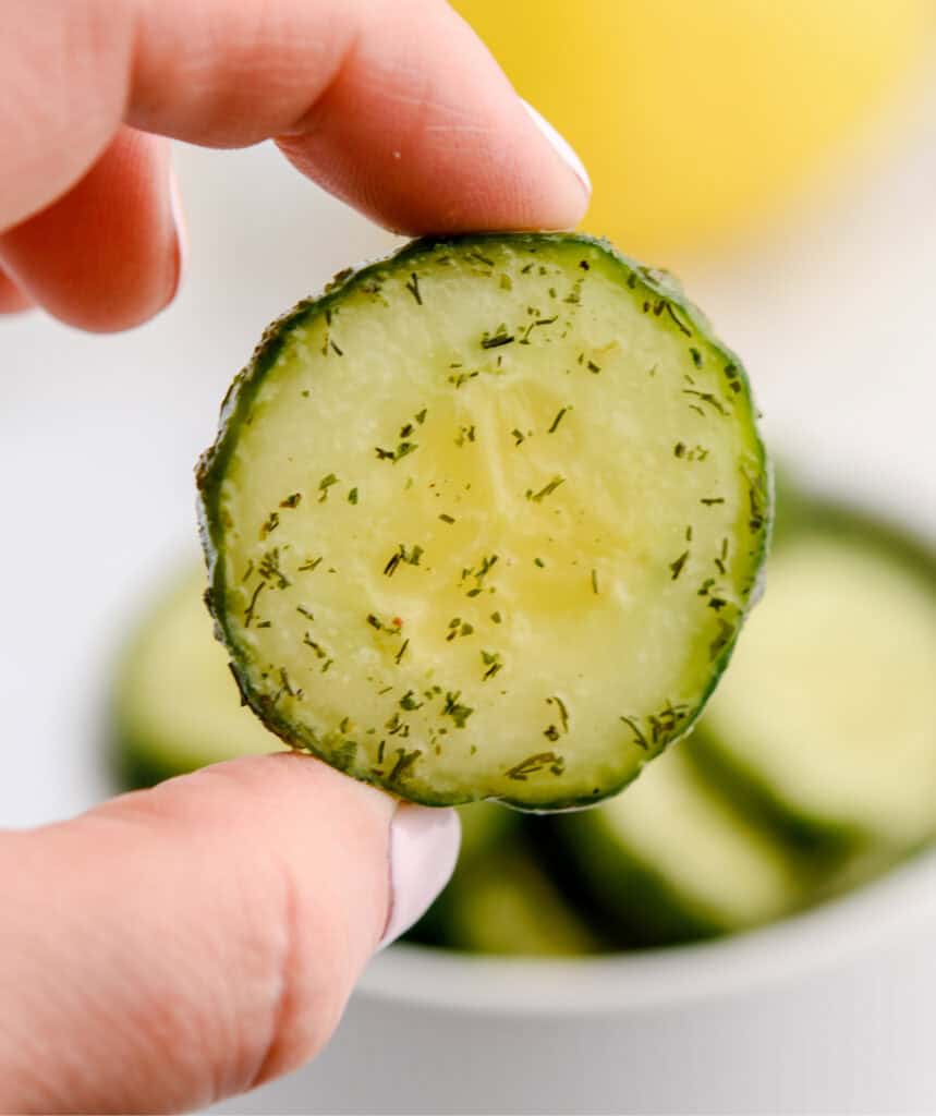 Hand Holding Cucumber Slice with Ranch Seasoning